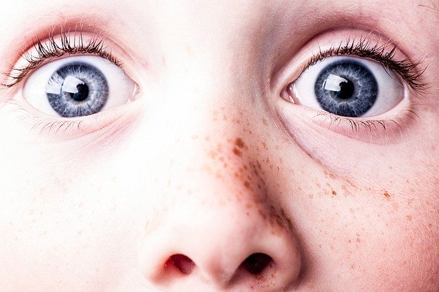 Detail chlapeckého obličeje s pihami a velkýma modrýma očima